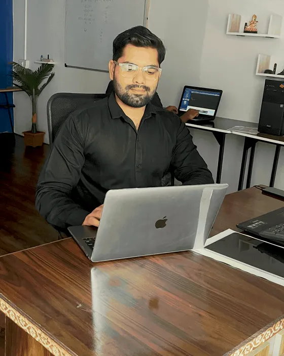 Dhanraj Chakravarti working on a laptop at his office desk in Jabalpur